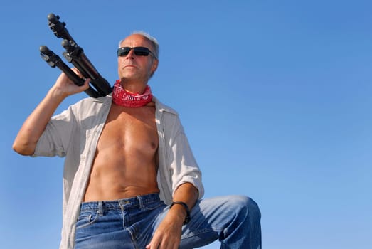 Handsome adventurer mature man, outdoors with a tripod