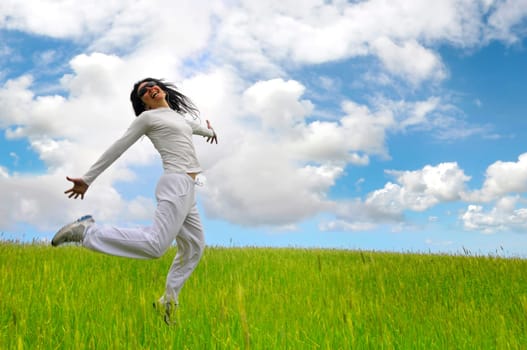 Woman jumping high in a green field