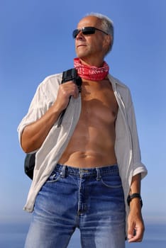Handsome mature model posing with a backpack outdoors