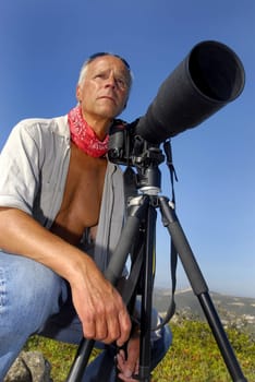 Handsome mature man posing with a big camera outdoors