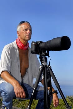 Handsome mature man posing outdoors with a big camera