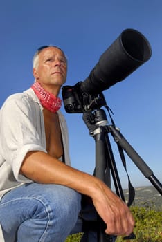 Handsome mature man posing with a big camera, outdoors