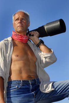 Mature man model posing with a big camera outdooors
