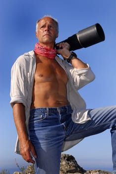 Handsome mature model posing with a big camera outdoors
