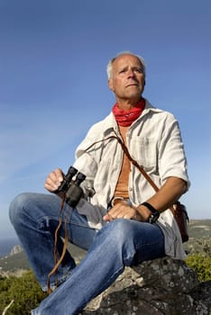 Mature man explorer posing outdoors with is binoculars