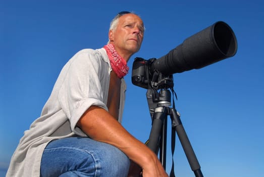 Handsome mature man adventurer posing with a big camera outdoors
