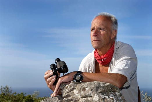 Explorer posing outdoors with is binoculars looking for adventure