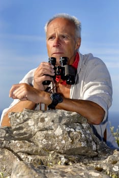 Mature man model posing outdoors with binoculars