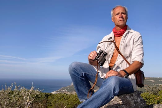 Model explorer posing outdoors with is binoculars looking for adventure