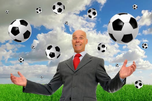 Mature businessman outdoors with soccer balls all around faling from the sky