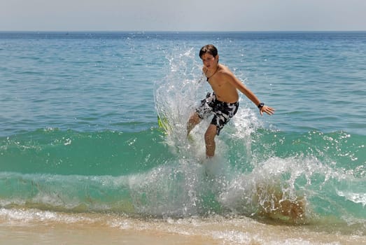 Boy jumping in the air with skimboard in the sea