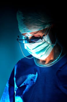 Doctor performing surgery in a dark background