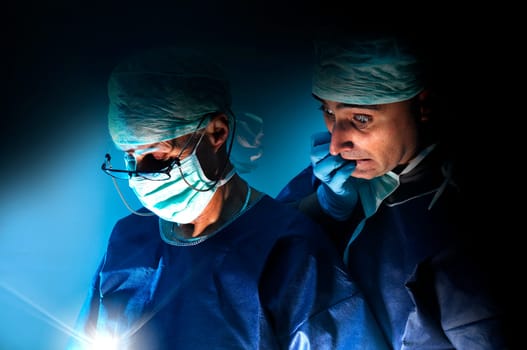 Doctors team in surgery in a dark background