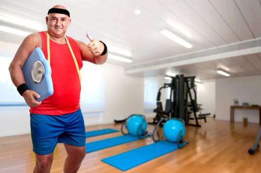 Large fitness man with weight scale in the gym