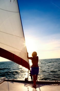 A woman on the bow of a sailboat looking out over the water