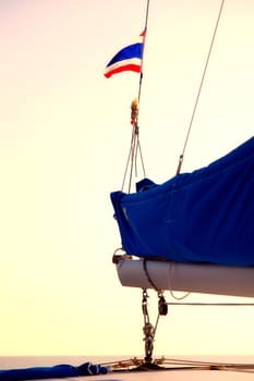 The Thai flag waves in the wind above the boom of a sailboat