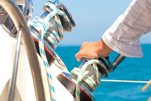 Sailboat captain rests his hand on one of the sail winches