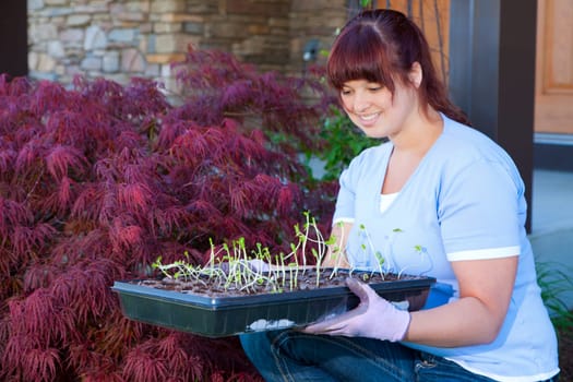 A young woman displays a tray of seedlings for her vegetable garden