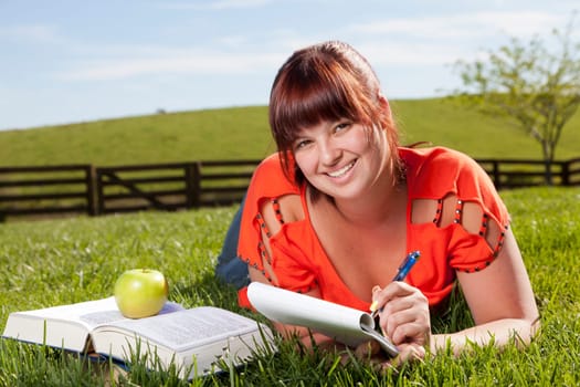 A college student is studying outside in the backyard