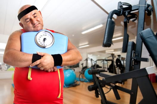 Large fitness man with weight scale in the gym