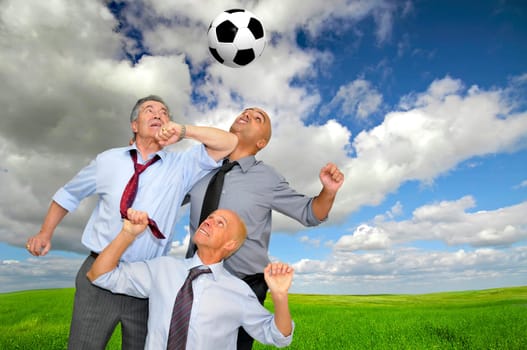 Businessmen playing soccer outdoors