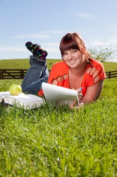 A college student is studying outside in the backyard