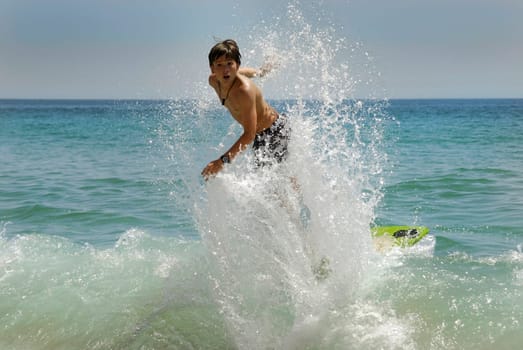 Boy jumping in the air with skimboard in the sea