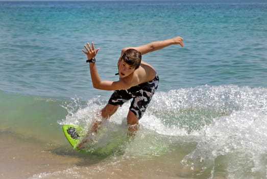 Boy jumping in the air with skimboard in the sea