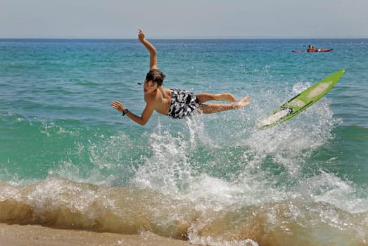 Boy jumping in the air with skimboard in the sea