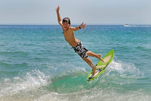 Boy jumping in the air with skimboard in the sea