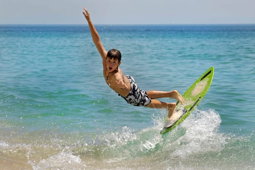 Boy jumping in the air with skimboard in the sea