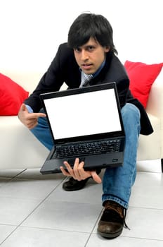 Young bussinessman in a couch with a laptop isolated in white