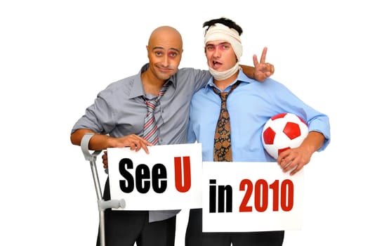 Two badly injured businessmen after a soccer match with cards saying See U in 2010, isolated in white