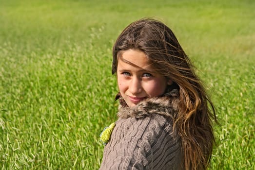 Beautiful young girl outdoors in a green field