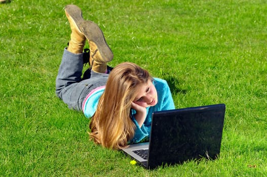 Girl playing with laptop in the grass