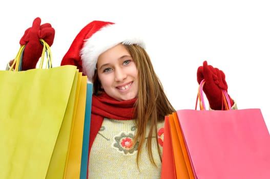 Beautiful young girl with santas hat and shopping bags isolated in white
