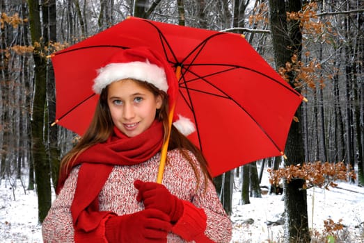 Beautiful young girl with red umbrella in the snow