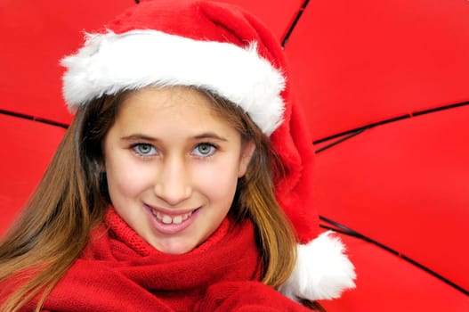 Beautiful young girl with santas hat and red umbrella