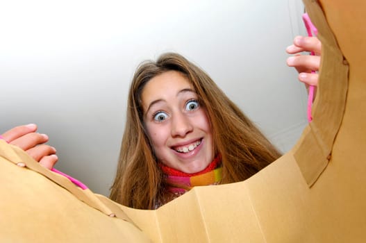 Beautiful young girl looking inside colorful bag isolated in white
