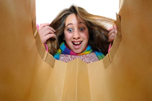 Beautiful young girl looking inside colorful bag isolated in white