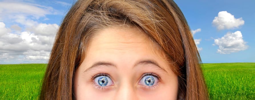 Young girl with planet eyes over a green field with blue cloudy sky