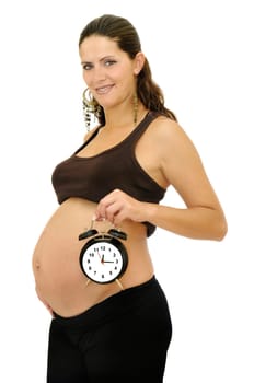 Pregnant woman holding a big alarm clock isolated in white