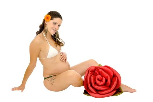 Pregnant woman with tattoo posing in bikini with a red rose isolated in white