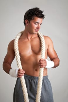 Muscular boxer posing with rope