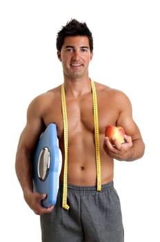 Muscular young man with apple and weight scale