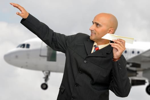 Businessman with paper plane and a jet plane passing behind