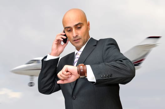 Businessman with cellphone and a jet plane passing behind