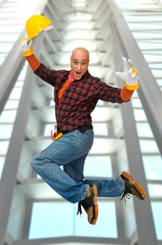 Happy construction worker jumping with a building as background
