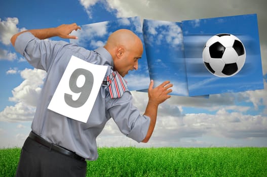 Businessman playing with a soccer ball in a green field