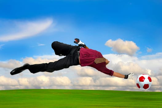 Businessman playing soccer outdoors in a green field